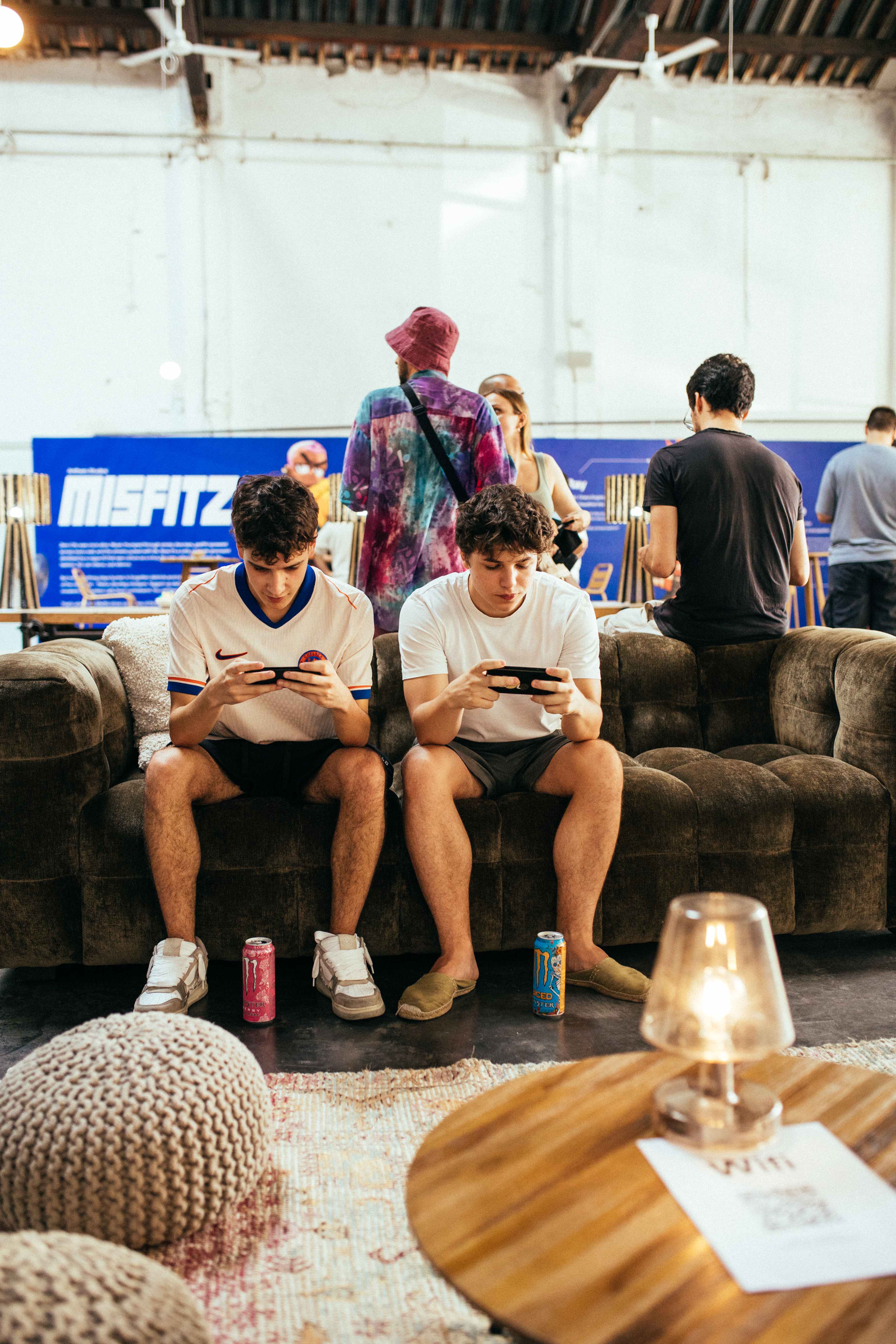 Two attendees sitting on a couch playing a game on their phones.